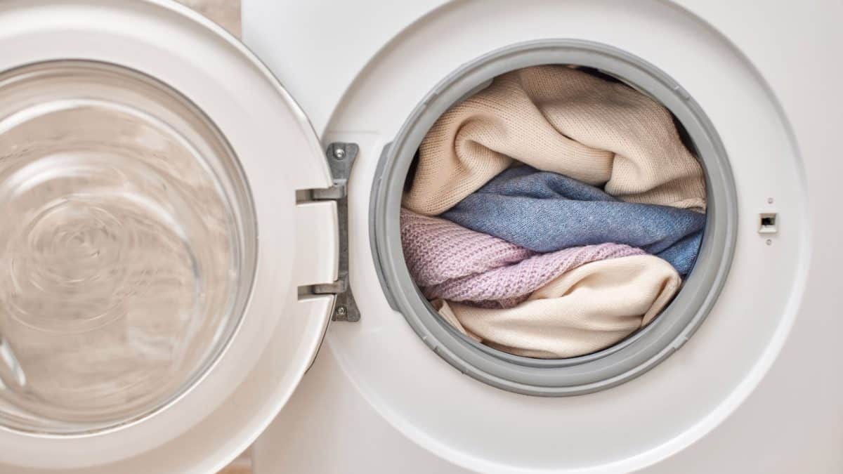 Open front-loader door showing a drum packed full with folded towels and knitwear