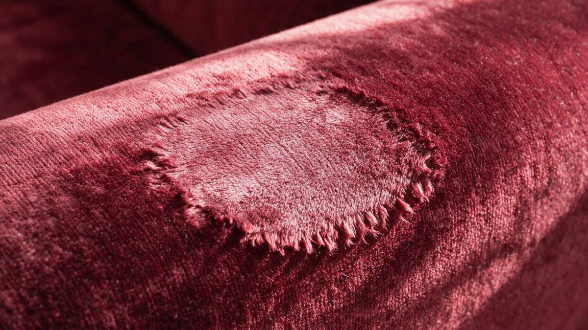 Burgundy cotton velvet with a flattened pressure mark reflecting light paler than the surrounding upright pile