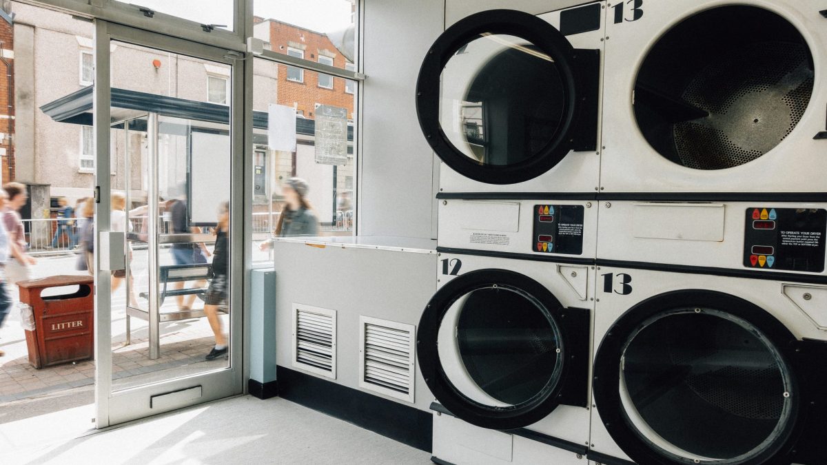 Rows of large front-loading commercial washers lining the wall of a self-service laundromat