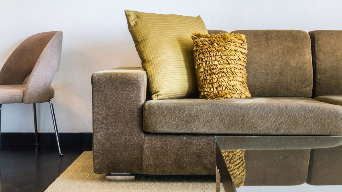 Taupe napped suede sofa with gold cushions beside a chair in a living room