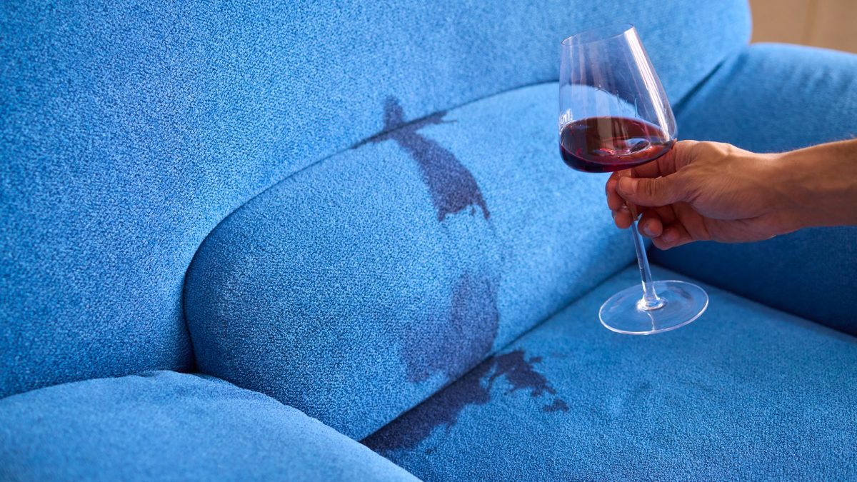 Red wine spilled across a blue couch cushion and running into the seam